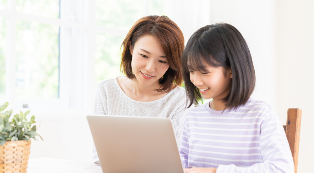 Asian girl and adult look at computer
